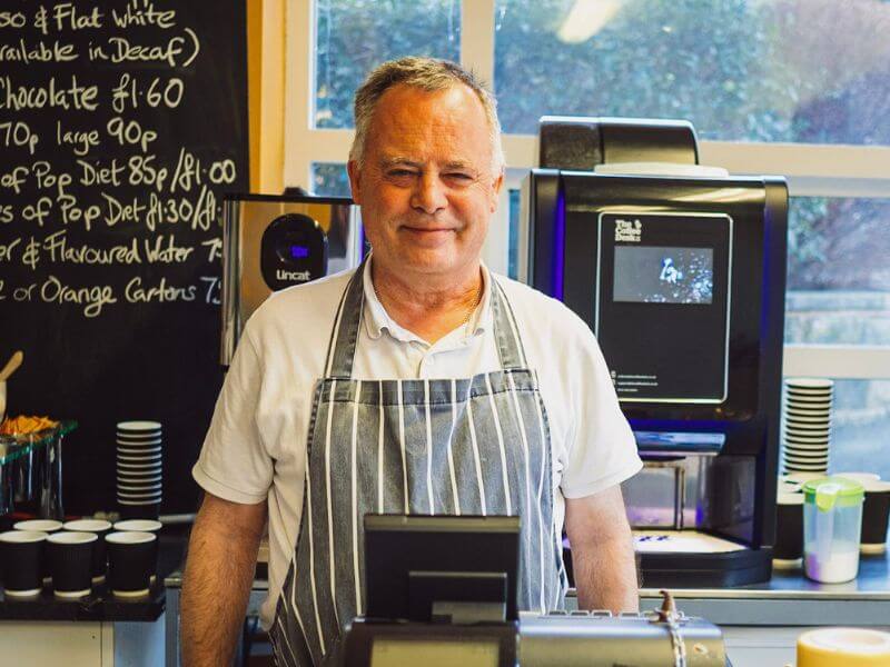 James smiling in a apron behind the cafe counter