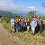 A collective of individuals positioned on a dirt road, showcasing camaraderie in a rustic outdoor environment.