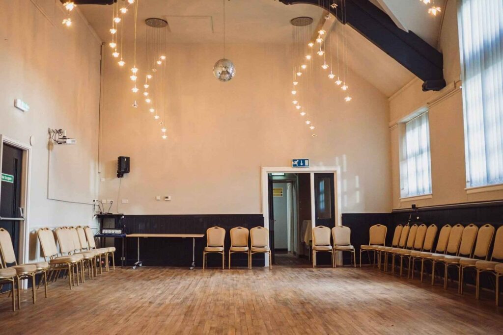 A large, well-lit room filled with chairs and stylish lights hanging from the ceiling.