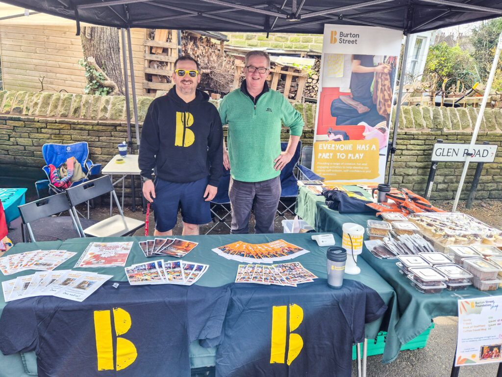 Two staff members at farmers' market talking about disability services in Sheffield