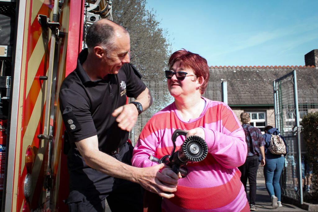 Adult with learning disability chatting with firefighter at Burton Street Foundation in Sheffield