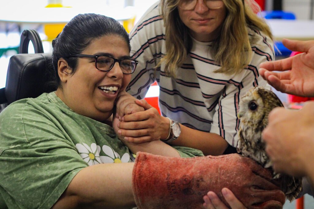 Disabled clients at Burton Street Foundation holding an owl and smiling